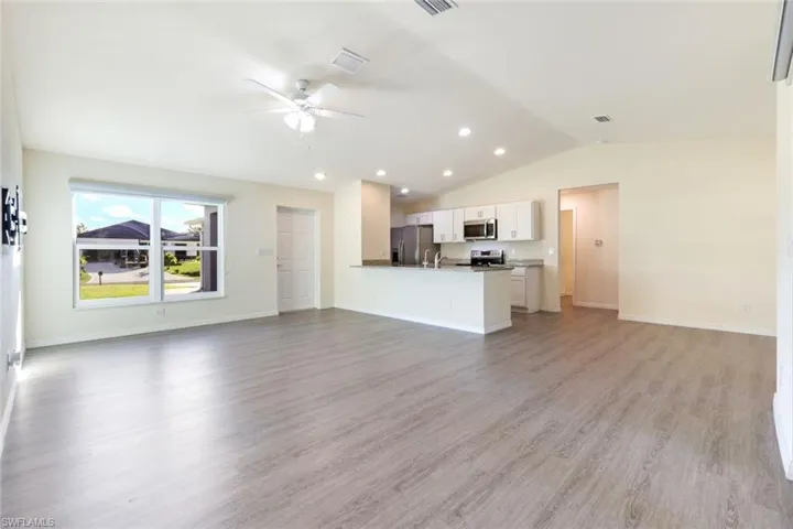Unfurnished living room with light wood-type flooring, vaulted ceiling, ceiling fan, and recessed lighting