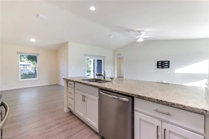 Kitchen with open floor plan, stainless steel dishwasher, healthy amount of natural light, light wood-type flooring, and recessed lighting