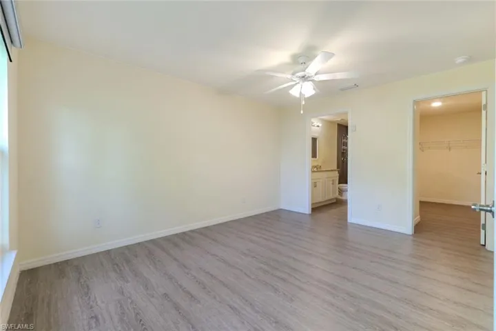 Unfurnished bedroom with light wood-style floors, a spacious closet, and ceiling fan