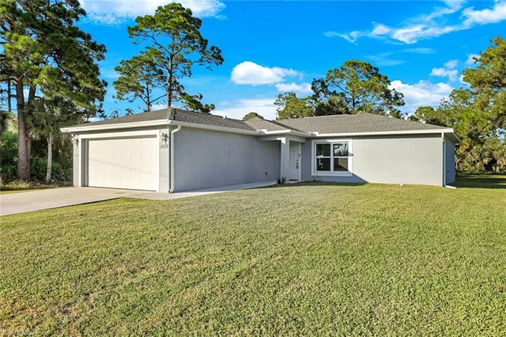 Ranch-style house with stucco siding, concrete driveway, a front yard, and a garage