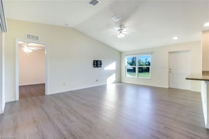 Unfurnished living room with light wood-type flooring, lofted ceiling, and a ceiling fan