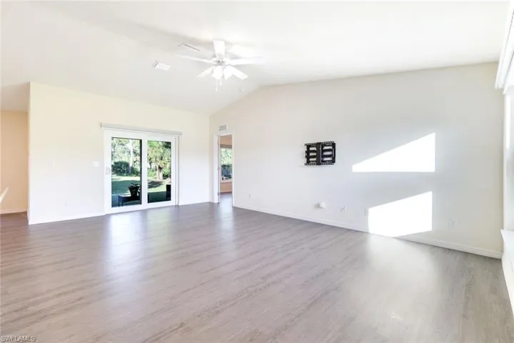 Unfurnished room featuring light wood-style floors, lofted ceiling, and ceiling fan