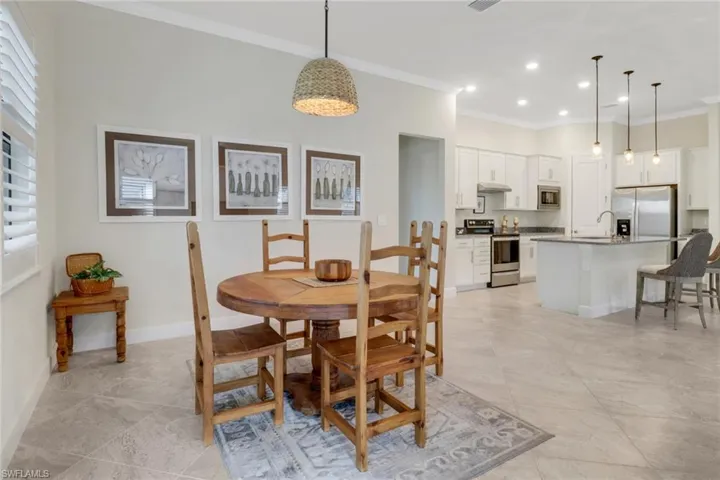 Dining area with ornamental molding and recessed lighting