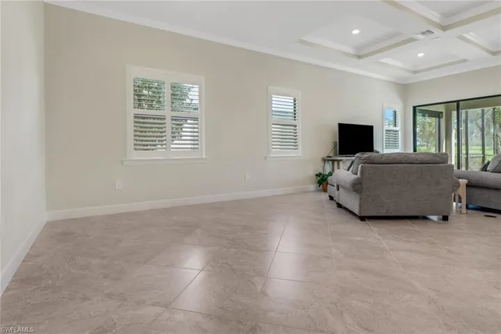 Living room with ornamental molding, beamed ceiling, coffered ceiling, and recessed lighting