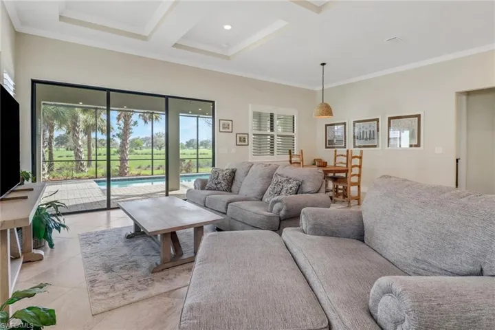 Living area with crown molding, light tile patterned floors, coffered ceiling, and beam ceiling
