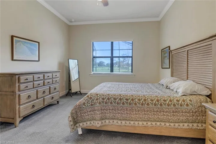 Bedroom with light colored carpet, crown molding, and ceiling fan