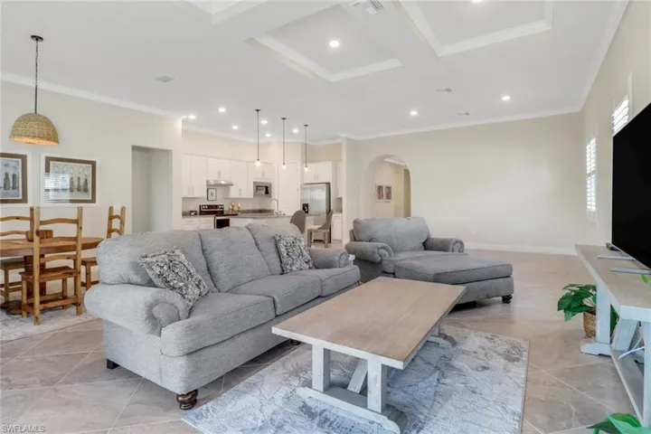 Living room with arched walkways, ornamental molding, recessed lighting, and coffered ceiling