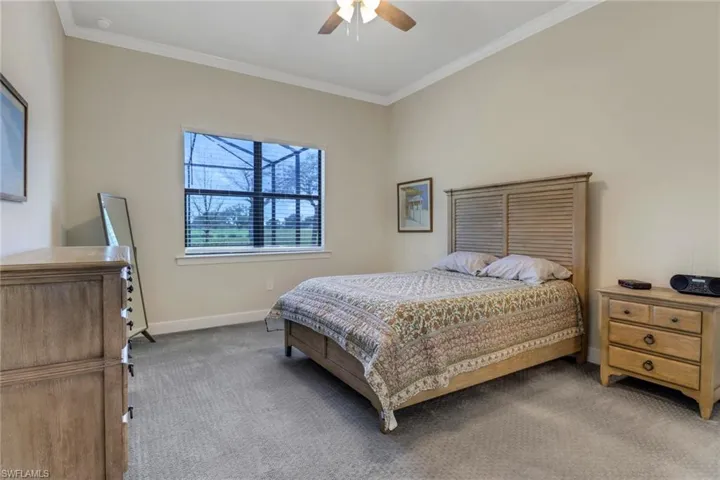 Carpeted bedroom featuring crown molding and ceiling fan