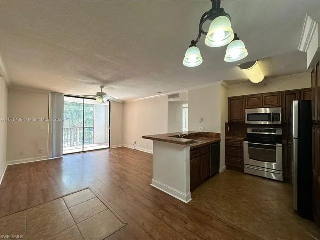 Kitchen featuring stainless steel appliances, kitchen peninsula, dark hardwood / wood-style floors, and a textured ceiling