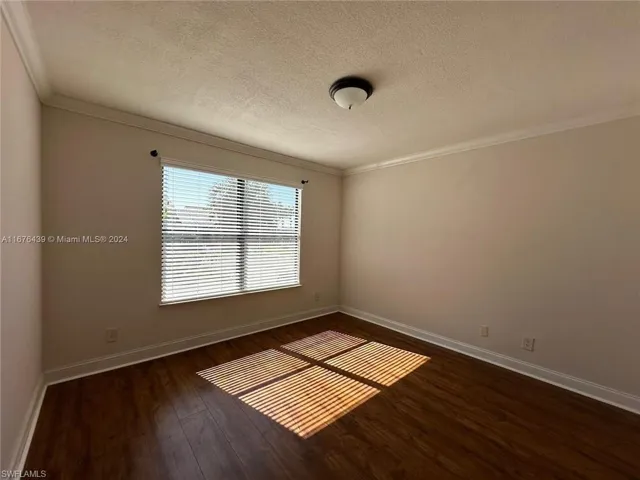 Spare room featuring ornamental molding, a textured ceiling, and dark hardwood / wood-style flooring