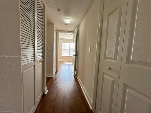 Hall featuring dark wood-type flooring and a textured ceiling