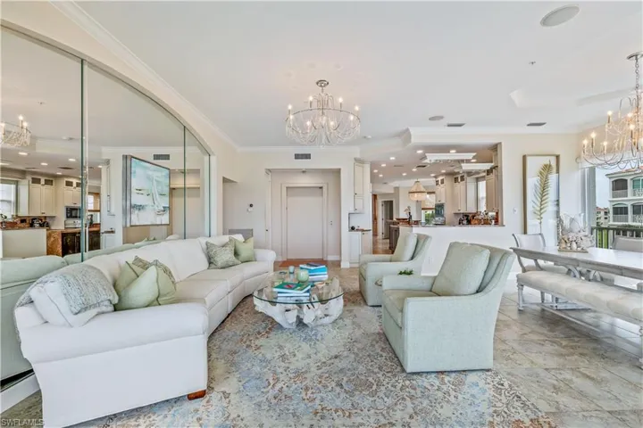 Living room with a notable chandelier, crown molding, and tile patterned flooring