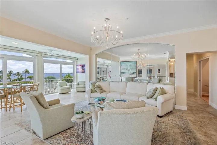 Living room with light tile patterned flooring, a notable chandelier, and crown molding