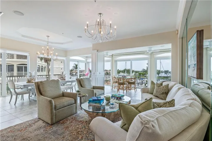Living room featuring decorative columns, tile patterned floors, a chandelier, and ornamental molding