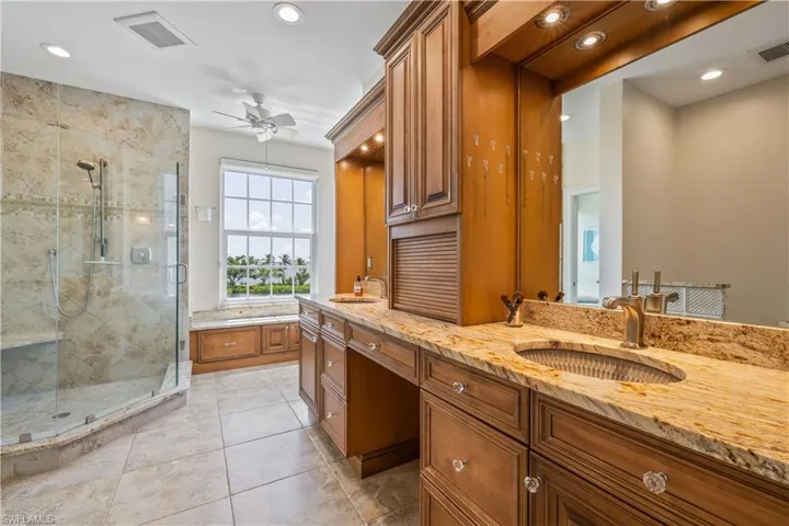 Bathroom with tile patterned floors, a shower with door, ceiling fan, and dual bowl vanity