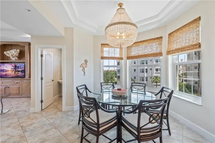 Dining area with light tile patterned floors, a chandelier, and a tray ceiling