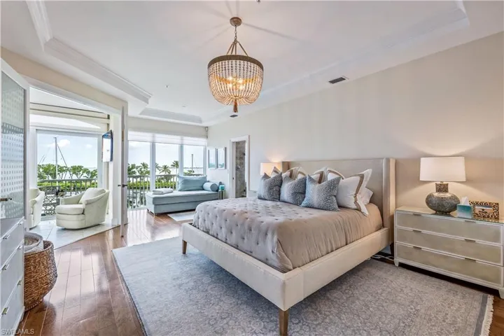 Bedroom featuring access to exterior, dark hardwood / wood-style floors, and a tray ceiling