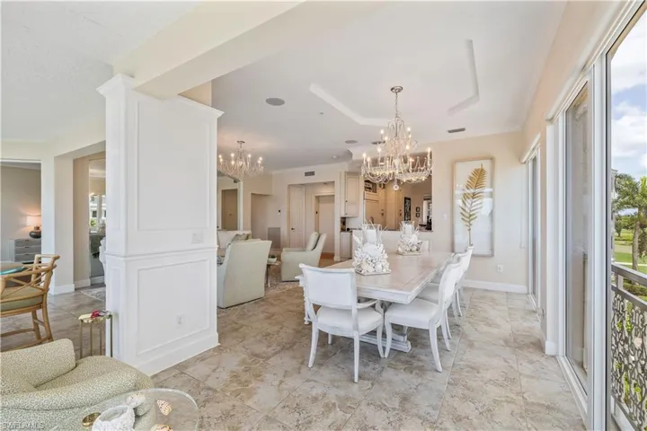 Dining area with an inviting chandelier, a wealth of natural light, light tile patterned floors, and a tray ceiling