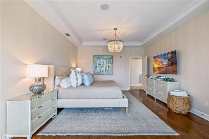 Bedroom featuring an inviting chandelier, dark hardwood / wood-style floors, and a raised ceiling