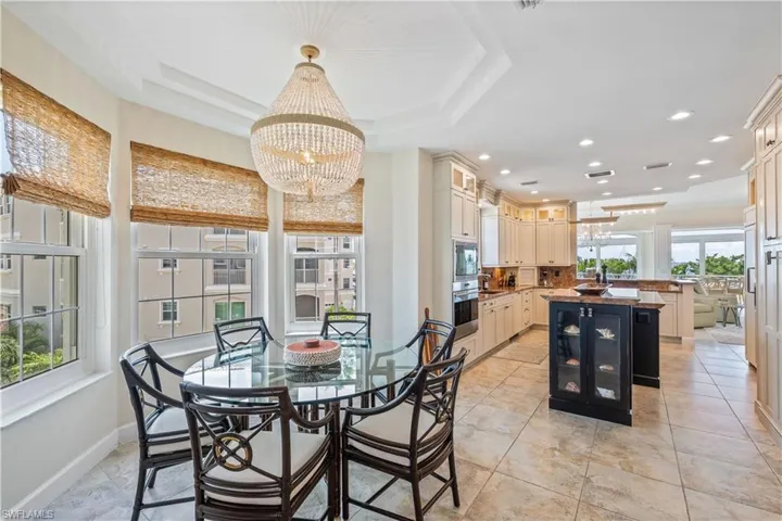 Tiled dining room featuring an inviting chandelier and a raised ceiling