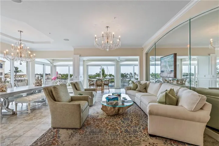 Living room with an inviting chandelier, light tile patterned flooring, a raised ceiling, and ornamental molding