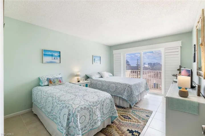 Bedroom with a textured ceiling, access to exterior, and light tile patterned floors