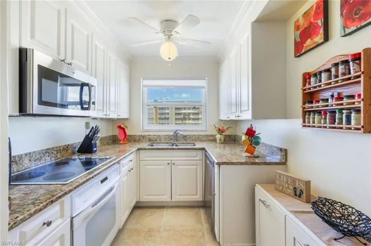 Kitchen featuring stone countertops, ornamental molding, sink, white cabinets, and white appliances