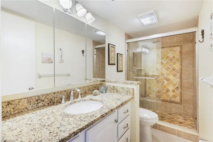Bathroom featuring vanity, tile patterned flooring, toilet, and walk in shower
