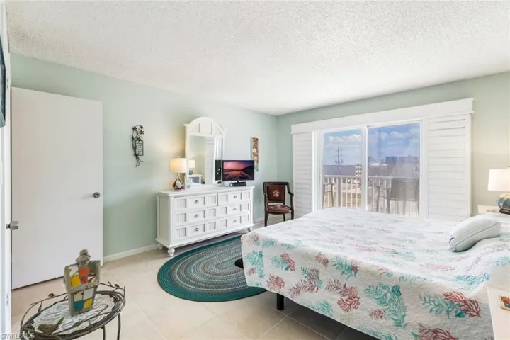 Bedroom featuring access to outside, a textured ceiling, and light tile patterned floors