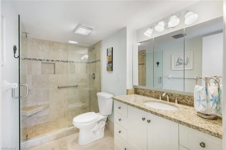 Bathroom with vanity, a shower with shower door, toilet, and tile patterned floors