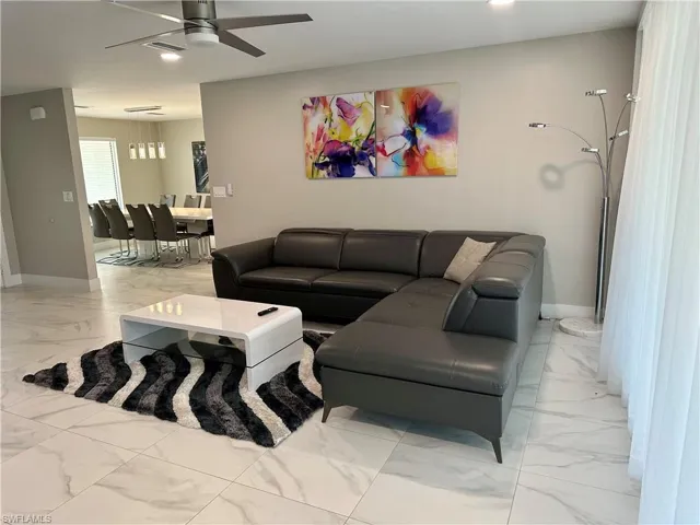 Living area featuring light marble finish floors, recessed lighting, and ceiling fan