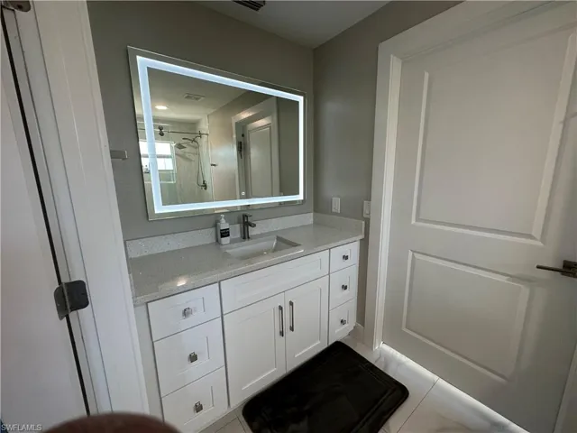 Bathroom featuring vanity, tiled shower, and light tile patterned floors