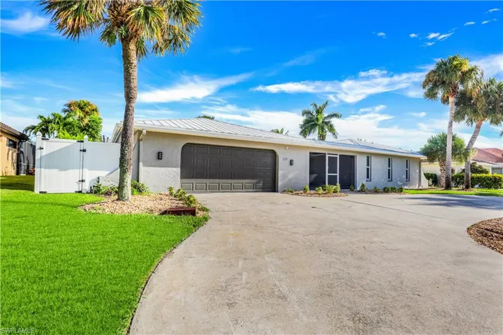 View of front facade with a gate, stucco siding, driveway, a garage, and a metal roof