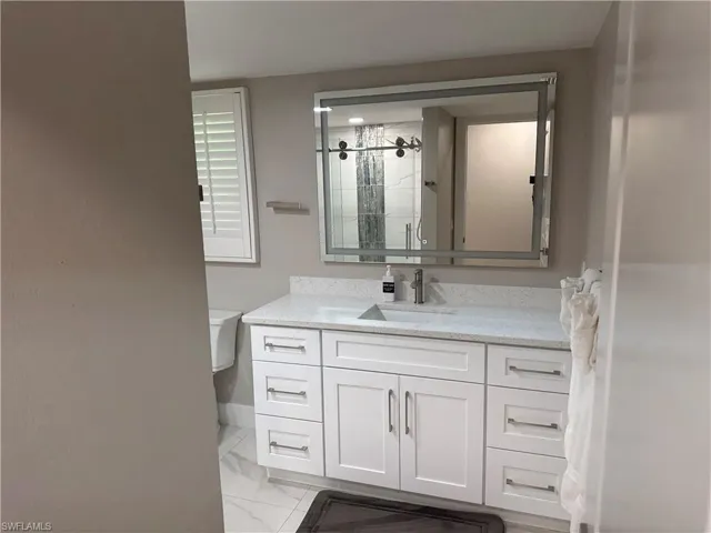 Bathroom featuring vanity, a stall shower, and light marble finish floors