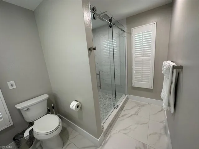 Full bathroom with light marble finish floors and a marble finish shower