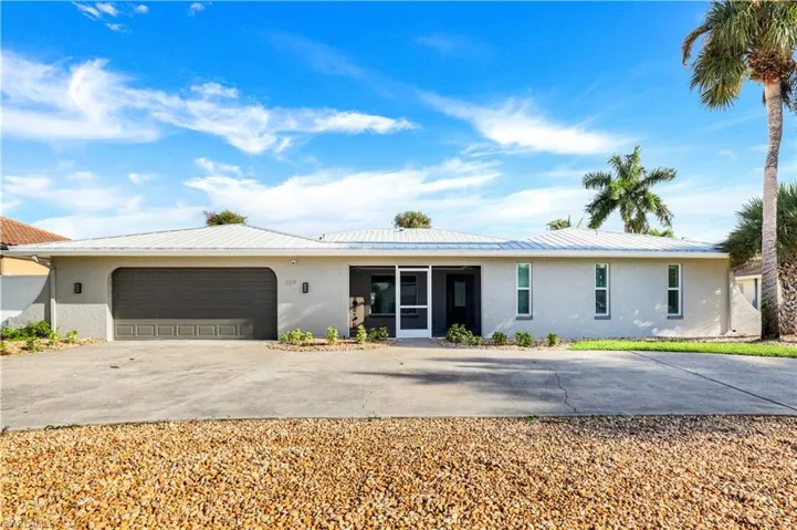 Single story home with stucco siding, concrete driveway, and a metal roof