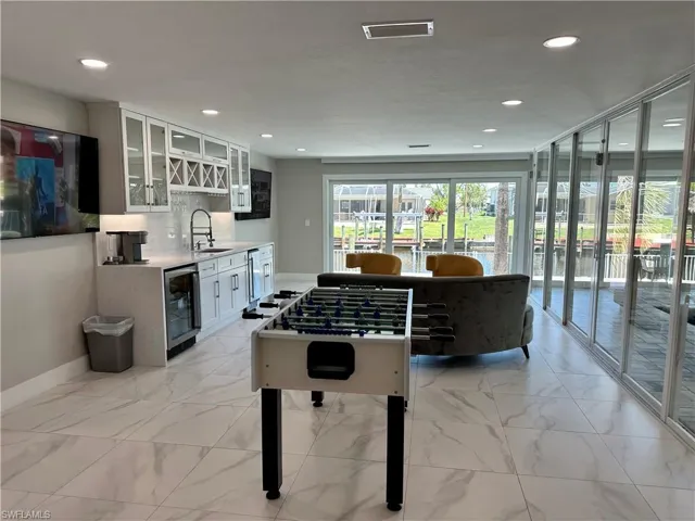 Recreation room featuring light marble finish floors, beverage cooler, recessed lighting, and wet bar