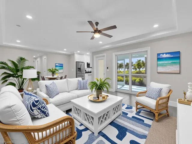 Living room with light wood-style flooring, ceiling fan, a raised ceiling, and recessed lighting