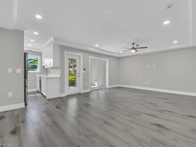 Unfurnished living room with light wood-style flooring, recessed lighting, a ceiling fan, and a tray ceiling