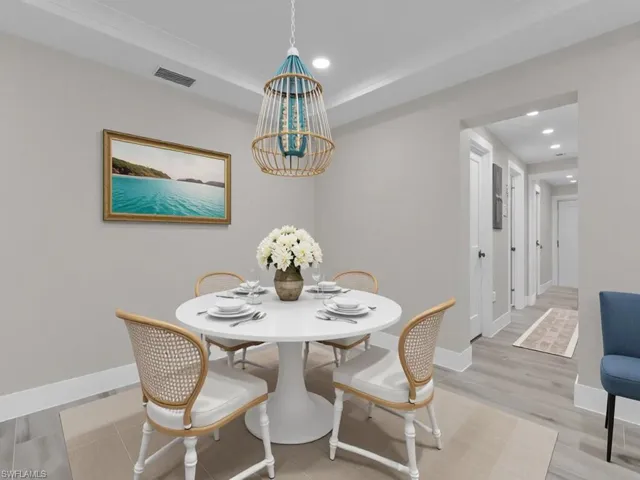 Dining room featuring light wood-type flooring, recessed lighting, a chandelier, and a tray ceiling