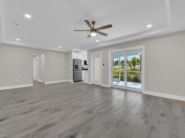 Unfurnished living room with light wood-type flooring, recessed lighting, ceiling fan, and a raised ceiling