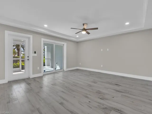 Empty room with a raised ceiling, light wood-type flooring, recessed lighting, and ceiling fan