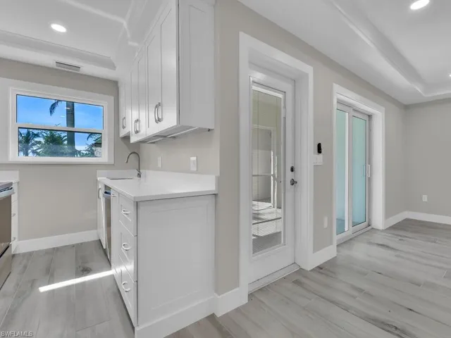 Kitchen with recessed lighting, a tray ceiling, light wood-style floors, white cabinetry, and light stone countertops