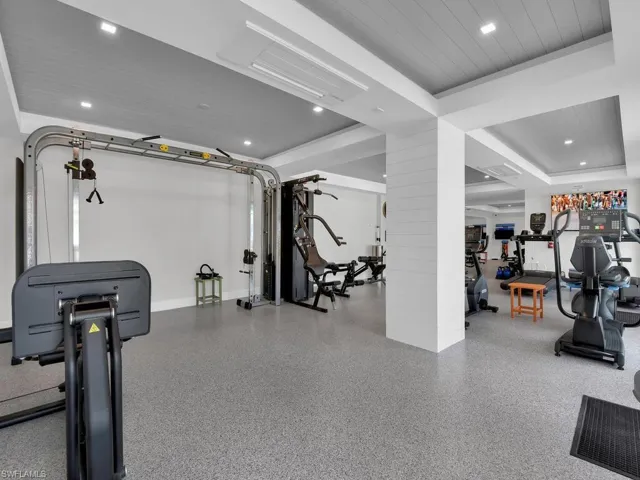 Workout area with recessed lighting and a tray ceiling