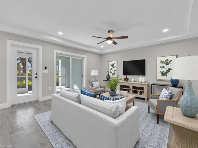 Living room with a tray ceiling, recessed lighting, wood finished floors, and ceiling fan
