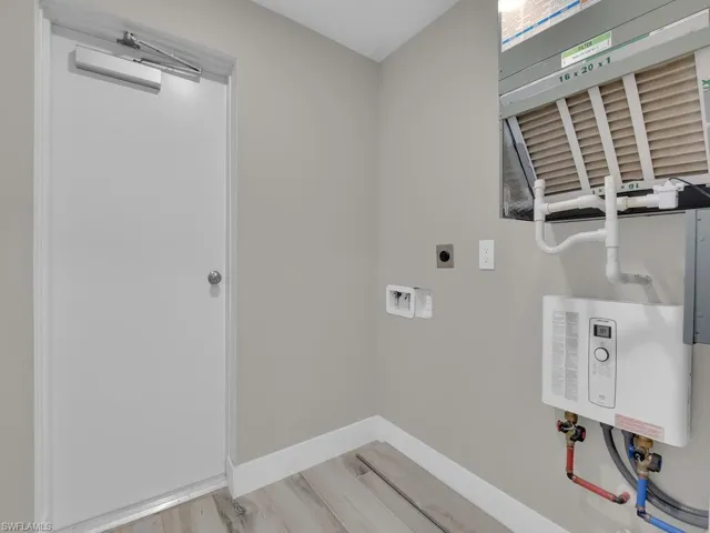 Washroom featuring washer hookup, tankless water heater, light wood finished floors, and hookup for an electric dryer