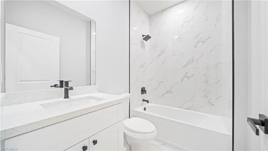 Full bath with shower / bathtub combination, vanity, and marble finish floors