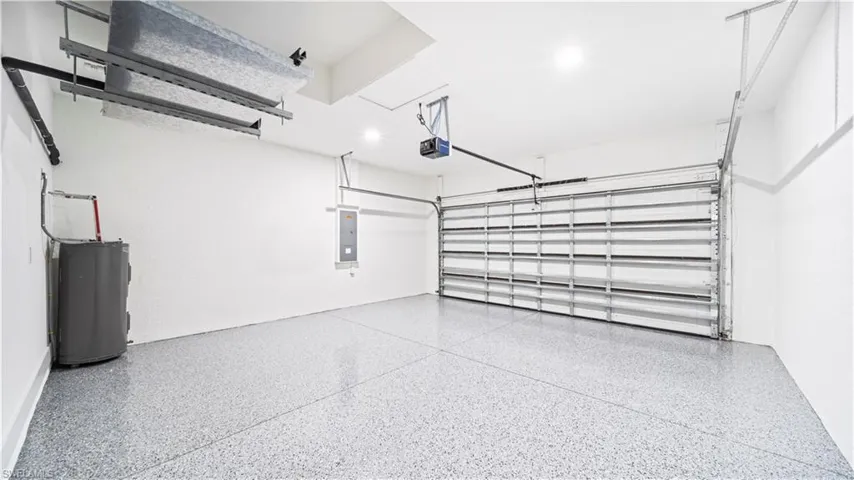 Garage featuring water heater, electric panel, and a garage door opener