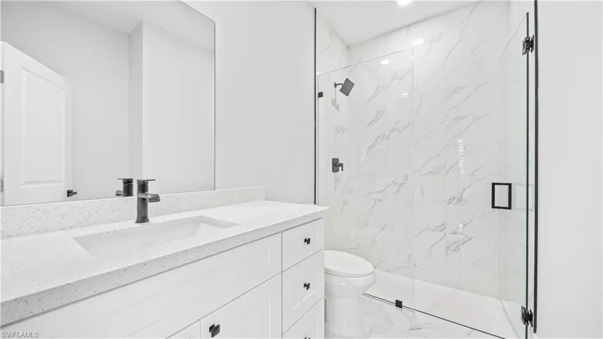 Full bath with vanity, a marble finish shower, and light marble finish floors