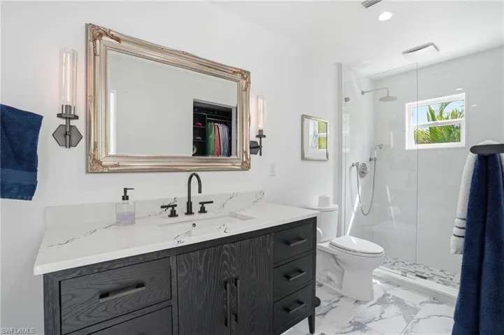 Bathroom featuring vanity, a stall shower, recessed lighting, a walk in closet, and light marble finish flooring - Virtually Edited Image